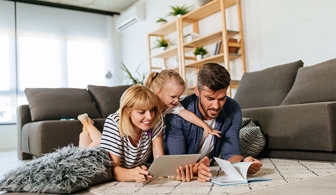 A happy family of three lying on a clean white rug