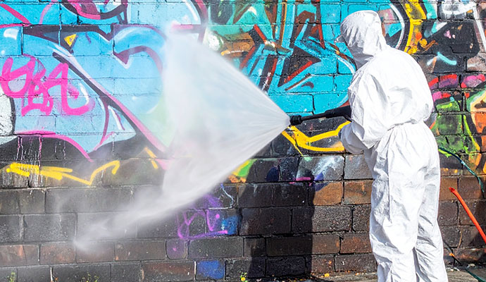 Professional removing graffiti using high-pressure wash