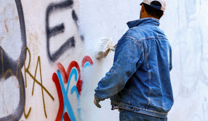 Professional painting over colorful graffiti on an urban wall