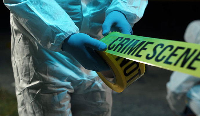 A professional unrolling yellow 'Crime Scene Do Not Cross' tape