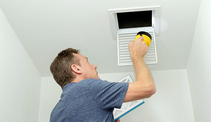 A person inspecting duct system using flash light