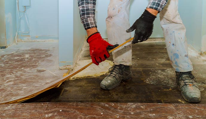 Contractor removing damaged flooring during water damage restoration and home repair process