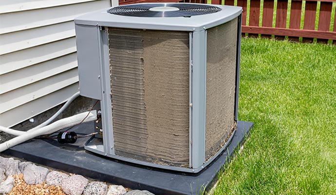 Outdoor HVAC condenser unit with significant layer of dust and debris