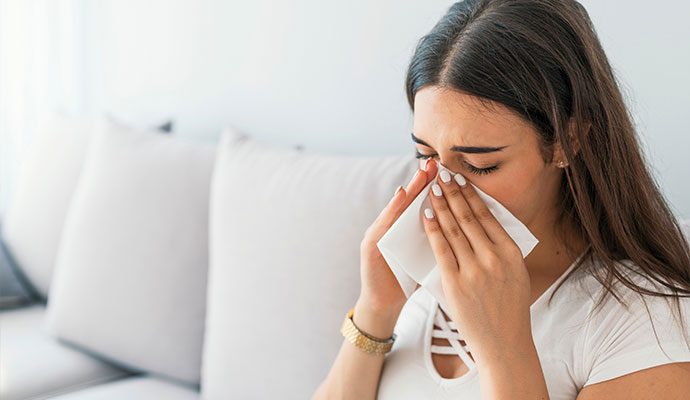 Woman sneezing and covering her face