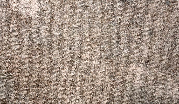 A close up of a brown carpet with large water stains