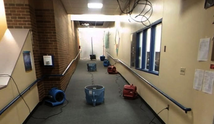 An indoor commercial hallway with several blue and red air movers